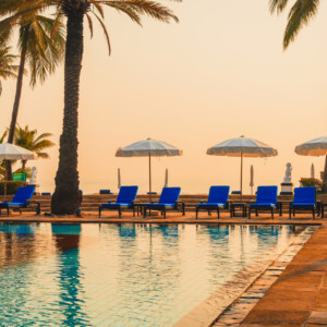 beautiful palm tree with umbrella chair pool in luxury hotel resort at sunrise times - holiday and vacation concept